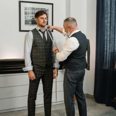 Tailor measuring a man for a custom suit in a stylish studio.